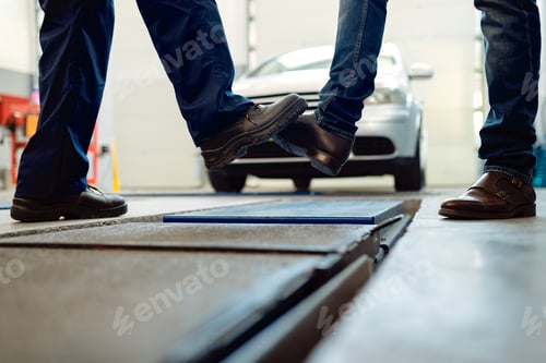 Preview: Close-up of men foot bumping at auto repair shop.