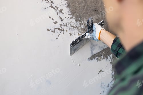 Preview: Hands man plasterer construction worker at work with trowel, plastering a wall, closeup.