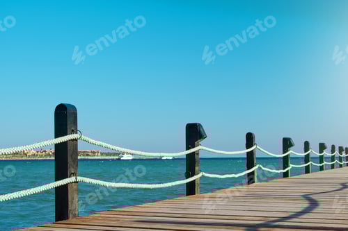 Preview: Wooden pier on sea stretching into distance beyond horizon on sunny summer day. Vacation and Travel