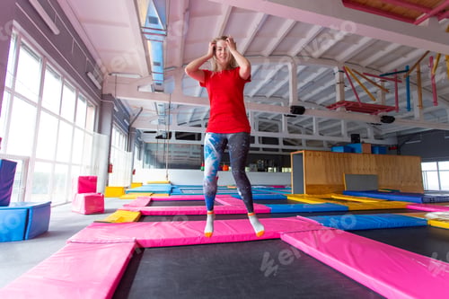 Preview: Fitness, fun, leisure and sport activity concept - Young happy woman jumping on a trampoline indoors