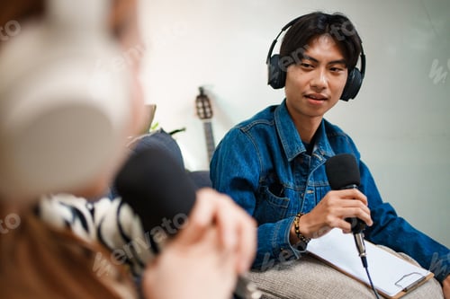 Preview: Young man speaking in podcast with headphones and microphone at home