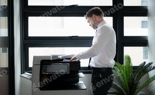 Preview: Businessman in office working with copier.