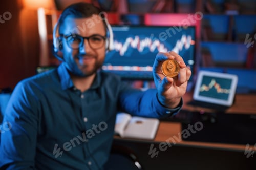 Preview: Holding bitcoin. Stock trader is working by pc indoors. Conception of exchange and money