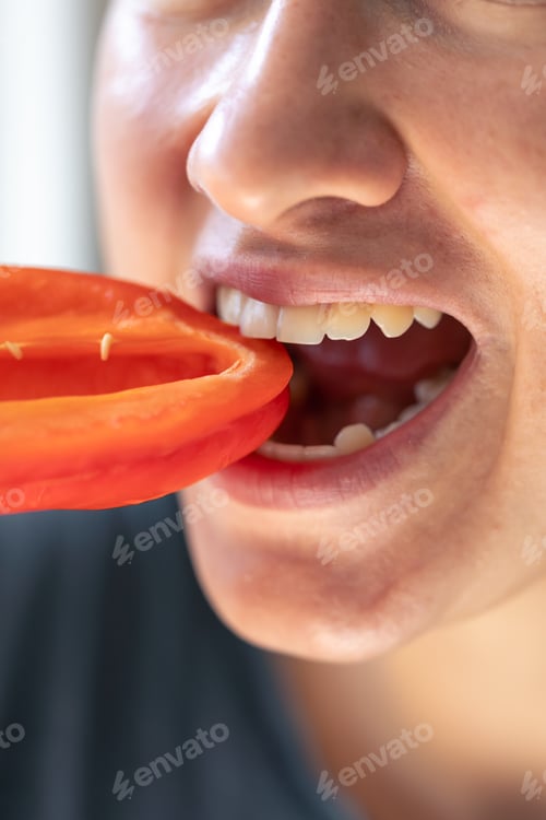 Preview: Detailed shot of a woman bites red bell pepper.