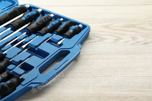 Preview: Set of screwdrivers in open toolbox on light wooden table, closeup. Space for text