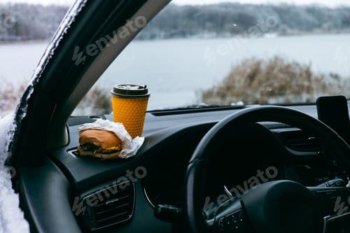 Preview: burger and coffee mug at car dashboard