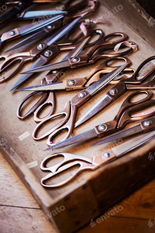 Preview: A tray of old dressmakers scissors of various sizes, some with angled blades.