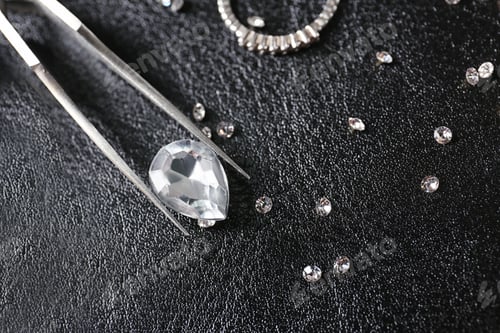 Preview: Jewels and tweezers on black leather surface