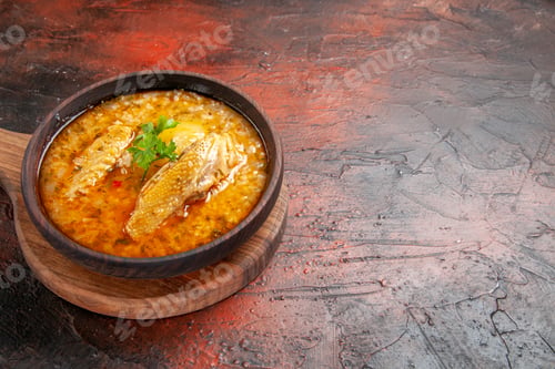 Preview: bottom view chicken soup in wooden bowl on chopping board on dark red background with free space