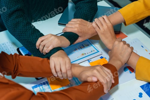 Preview: businesspeople putting hands together above the table express unity and support.