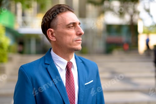 Preview: Mature handsome Italian businessman relaxing outside of the building