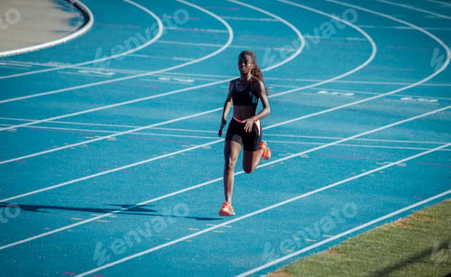 Preview: A black athlete of African origin trains her speed on a blue athletics track.