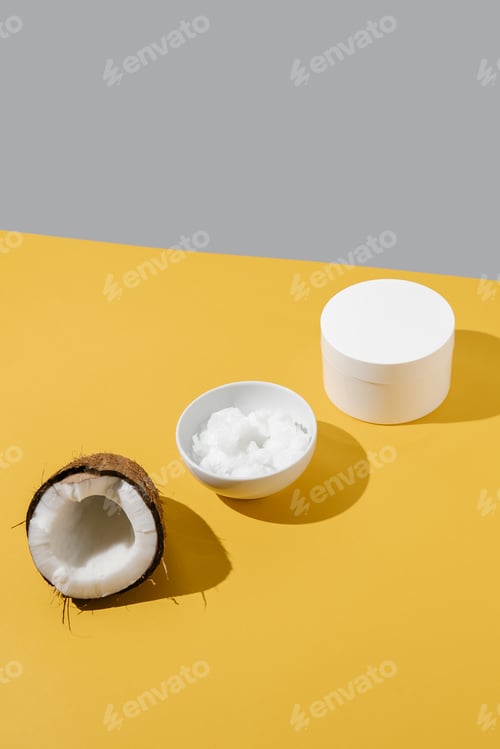 Preview: Half a coconut, coconut oil and a jar of coconut cream on a yellow background