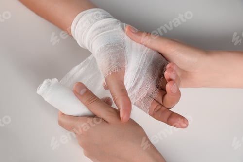 Preview: Doctor applying bandage onto patient's hand on white background, top view. Closeup