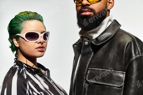 Preview: Stylish multicultural couple poses confidently in sunglasses in modern studio setting