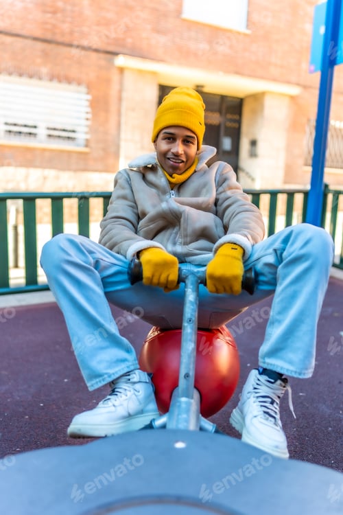 Preview: Young man having fun riding a playground spring rider in winter
