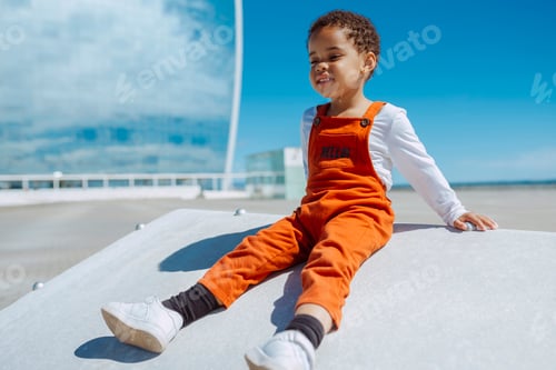 Preview: Cute african baby toddler sits by the sea at city