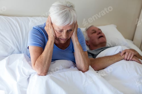 Preview: Senior woman getting disturbed with man snoring on bed