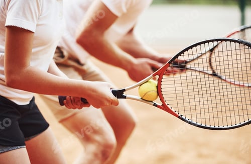 Preview: Side view. Coach teaching female student tennis game in the court outdoors