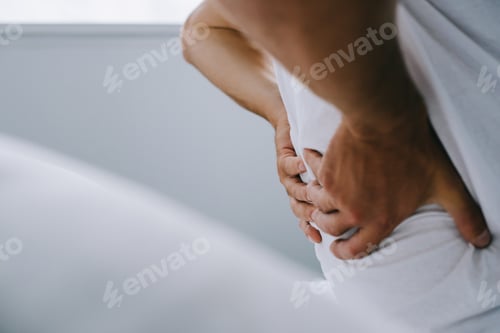 Preview: close-up partial view of man suffering from back pain on bed