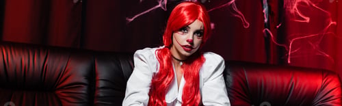 Preview: redhead woman with ponytails and halloween makeup on black couch and dark background with spiderweb,