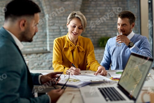 Preview: Happy woman signing paperwork while being with her husband on a meeting with insurance agent.