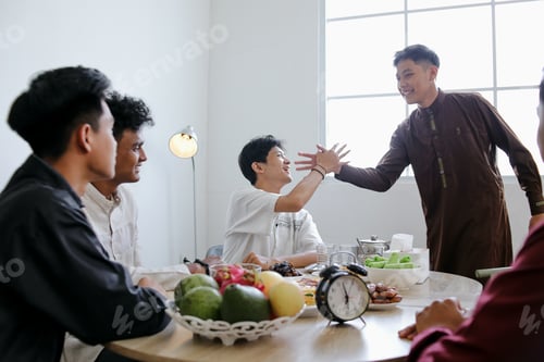 Preview: Muslim Friends Shaking Each Other Hands in Dining Table During Ramadan Celebration