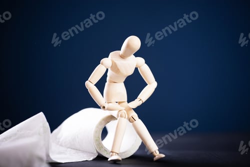 Preview: Wooden figure sit on a roll of toilet paper. Concept of the problem with digestion.