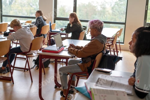 Preview: Students Working at Desks with Laptops in Classroom