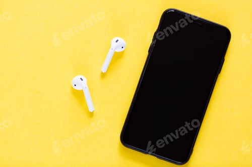 Preview: Flat lay with smartphone and wireless headphones on yellow background with copy space