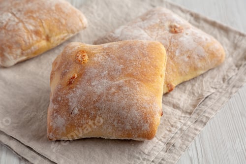 Preview: Homemade Cheese Ciabatta Buns on a white wooden background, side view.