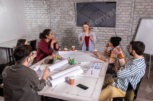 Preview: Group of modern business people in casual wear discussing architectural designs in office.