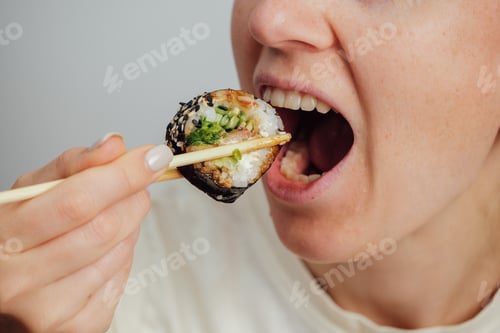 Preview: Close-up of woman eating sushi roll with chopsticks