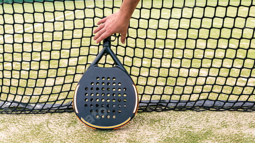 Preview: Professional monitor of padel holding black racket behind the net. Game concept