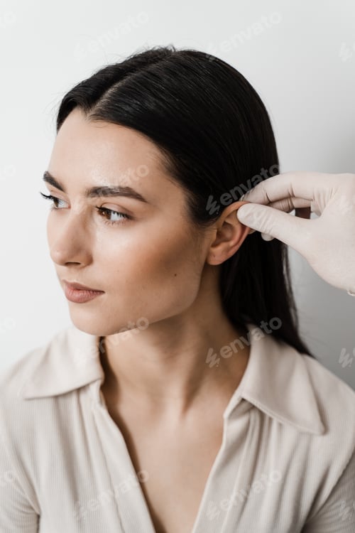 Preview: Otoplasty surgery surgeon inspects girl's ears before cosmetic ear reshaping procedure