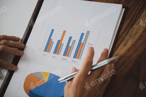 Preview: Closeup view of female entrepreneur looking through a business paperwork report with graphs