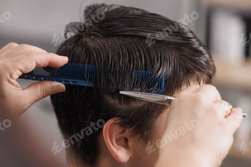 Preview: Close-up of a professional hairstylist cutting wet hair with scissors and a comb in a modern salon