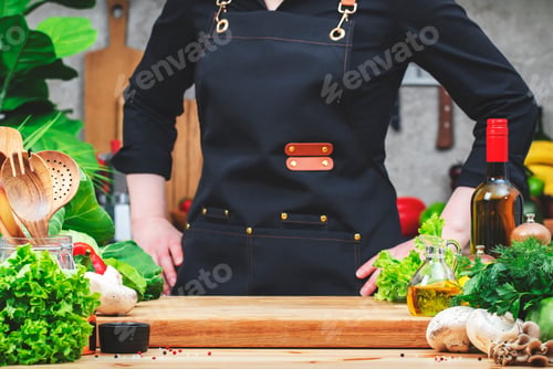 Preview: Chef in black stands confidently with hands on hips, about to start cooking