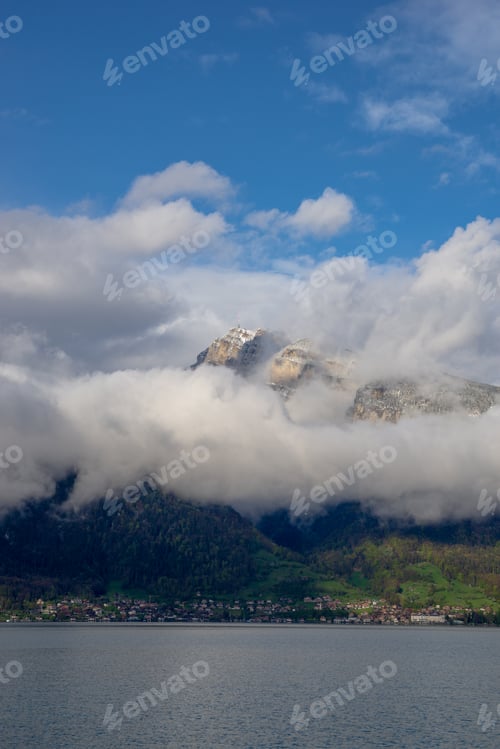 Preview: Scenic view of mountains, clouds and a town reflected near a tranquil water