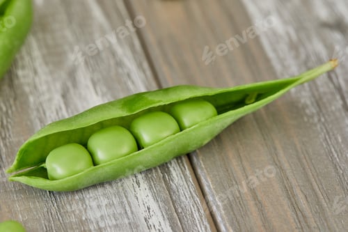Preview: Opened pods of fresh green peas on wooden background