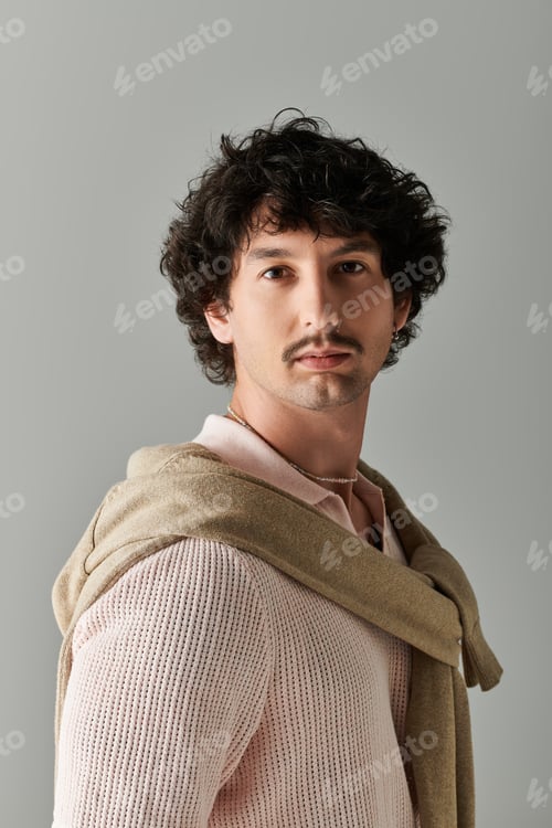 Preview: Stylish young man showcases modern fashion with confidence in a minimalist setting