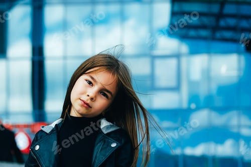 Preview: Little girl’s portrait in urban setting at blue glass wall