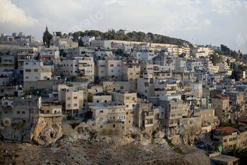 Preview: A panoramic view of densely packed residential buildings on a hillside under a clear sky at dusk.