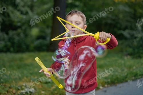 Preview: cute little boy blowing soap bubbles in park