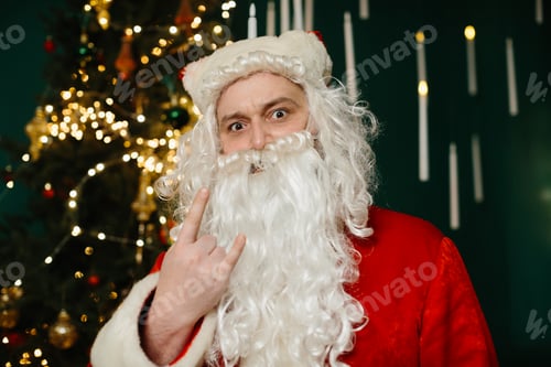 Preview: Santa claus gesturing rock and roll sign by christmas tree