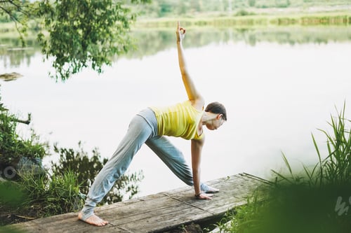 Preview: Young smiling woman practice yoga outdoors
