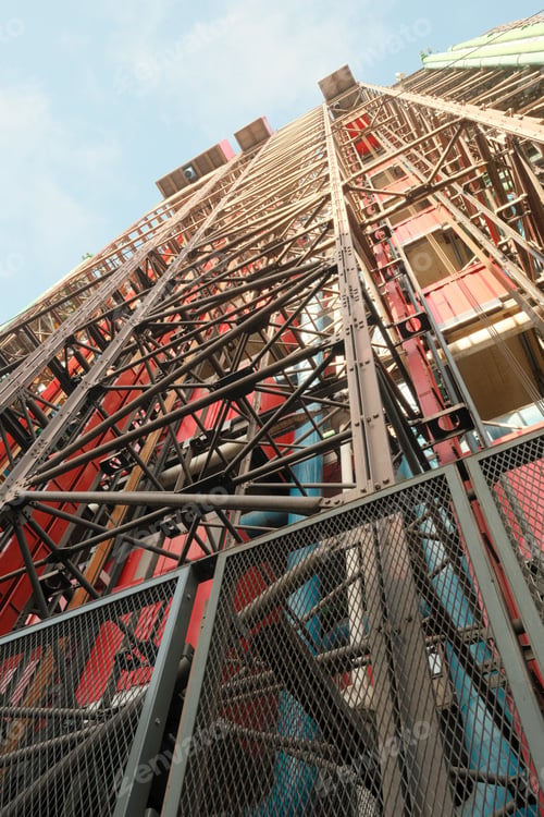 Preview: a tall metal structure in front of buildings with many colors