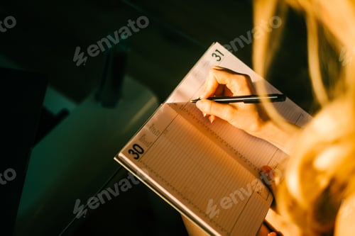 Preview: Caucasian woman making notes at home office.