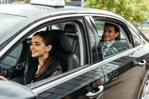 Preview: Smiling female taxi driver and businessman in car