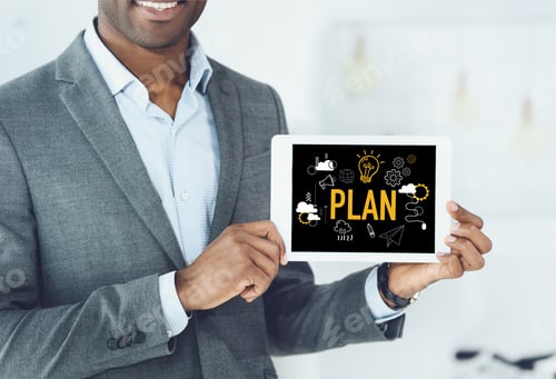 Preview: cropped image of smiling african american man showing digital tablet with word plan and business